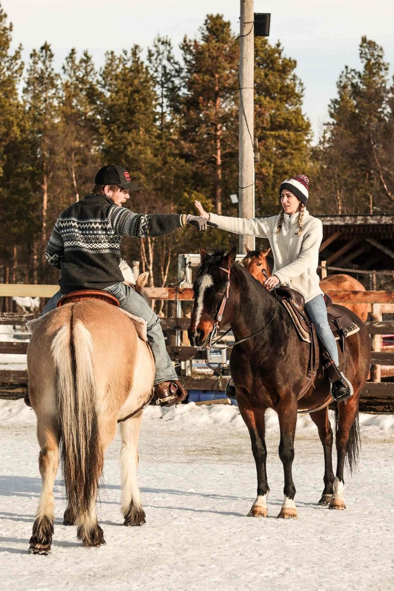 Two riders with their horses in the snowy paddock
