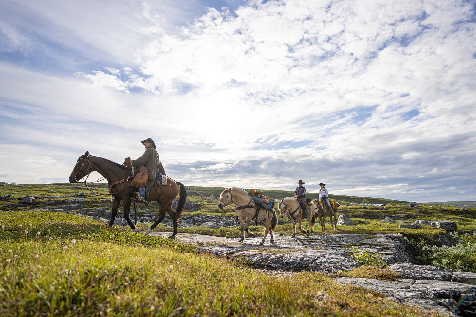 Riders crossing the open plateau under a wide sky