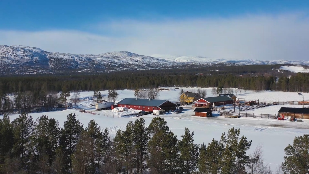 Flatmoen farm from above in winter, with the mountains behind